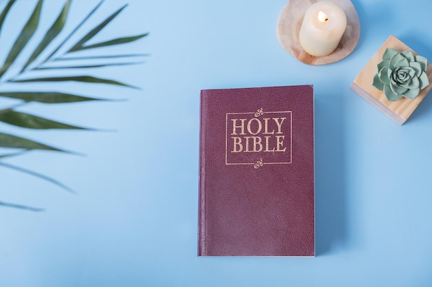 Photo christian holy bible and palm leaf with sandle on blue background flat lay top view