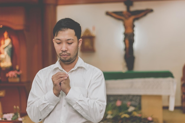 神からの祝福を求めるキリスト教徒の男性、イエス・キリストに祈るアジア人男性