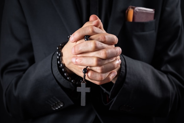 キリスト教の人の祈り、控えめなイメージ。黒のスーツを着た男または説教を描いている司祭の手