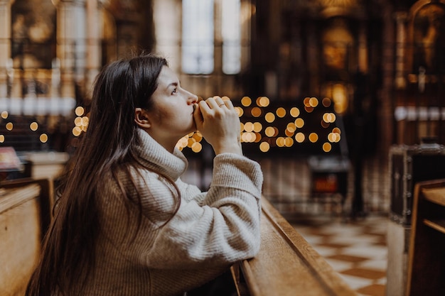 Christian woman prays in church Hands crossed on wooden table Christian Background