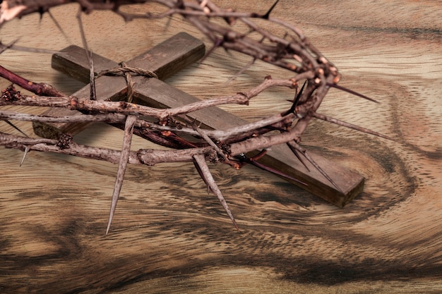 Christian wooden cross and crown of thorns on the desk