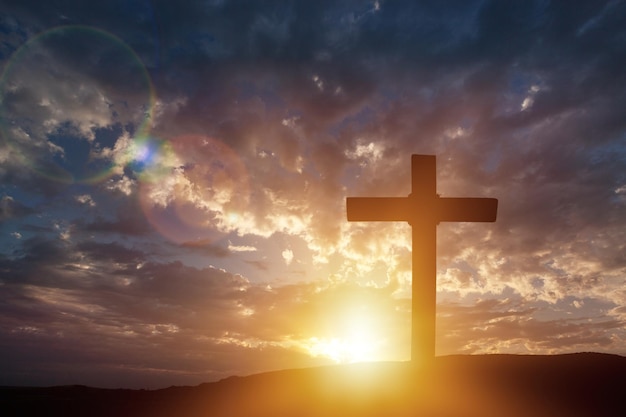 Christian wooden cross on sunset background.