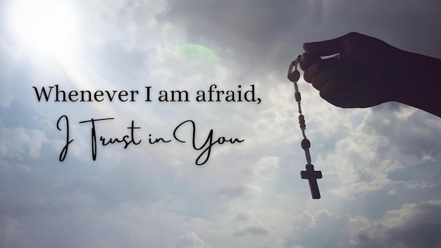 Christianity inspirational quote Whenever I am afraid I trust in You With hand holding Rosary with sky background
