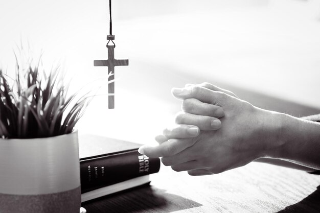 Photo christians praying and worshiping with hands together brightly lit bible and cross background