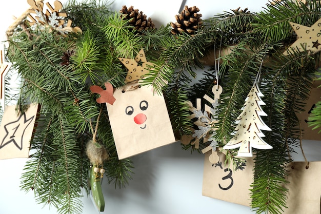 Christmas Advent calendar with spruce twigs hanging on wall.