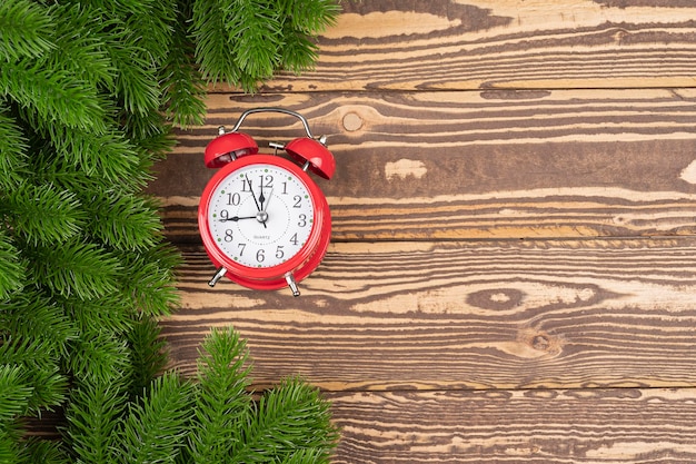 Christmas alarm clock with pine branch on wooden background with copy space for your text