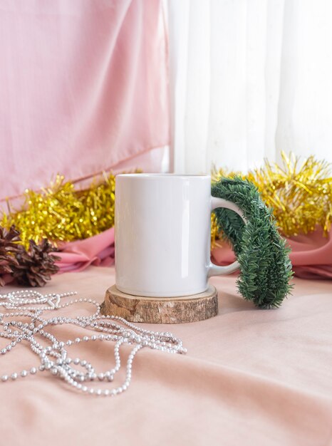 사진 크리스마스와 새해의 미니멀리즘 컨셉입니다. 제품 머그를 특징으로 하는 구성. 크리스마스와 새해 장식으로 나무에 머그