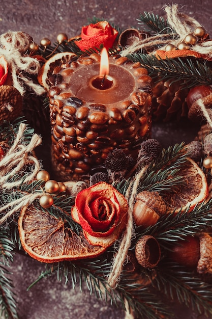 Рождественский ароматный эко-венок, украшенный кожурой мандариновых роз с зажженной кофейной свечой