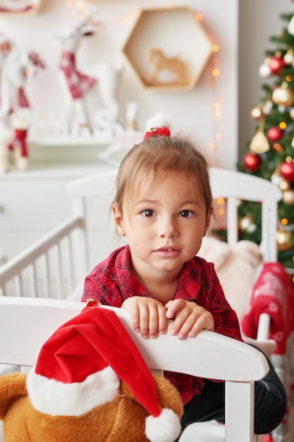 クリスマスの赤ちゃん。子供部屋の白いベッドで少し微笑んでいる女の子