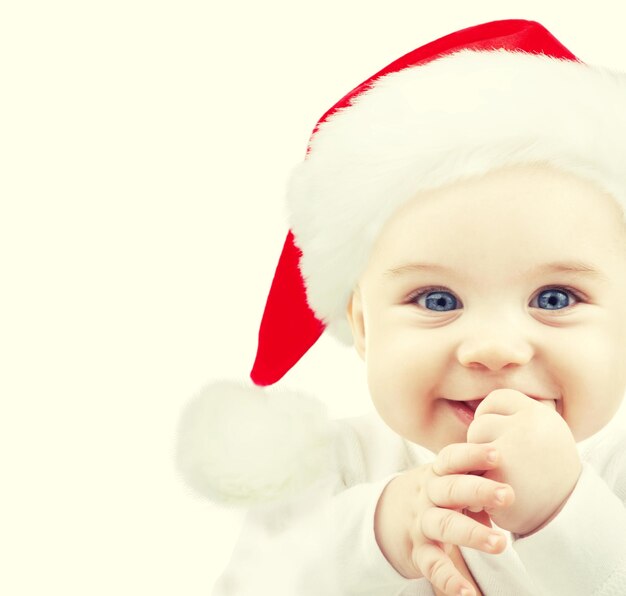 Foto concetto di natale, infanzia, infanzia e persone - bambino felice in cappello della santa sopra bianco