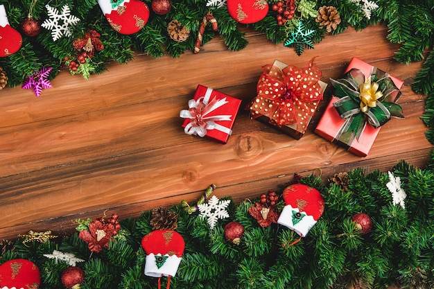 Christmas background, border decorate with pine branches gift socks and festive ornaments, natural wood background copy space in middle are with three presents.