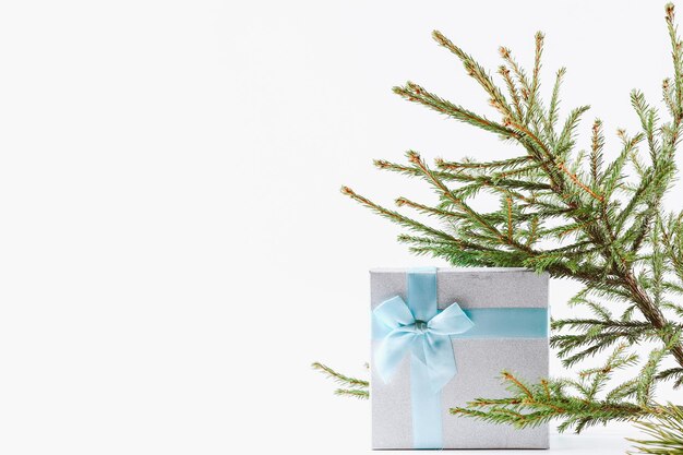 Christmas background a box with a gift tied with a ribbon and a spruce branch