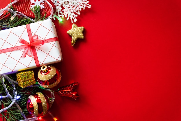 Christmas background. Christmas gift box with red ball and pine cones on red background.