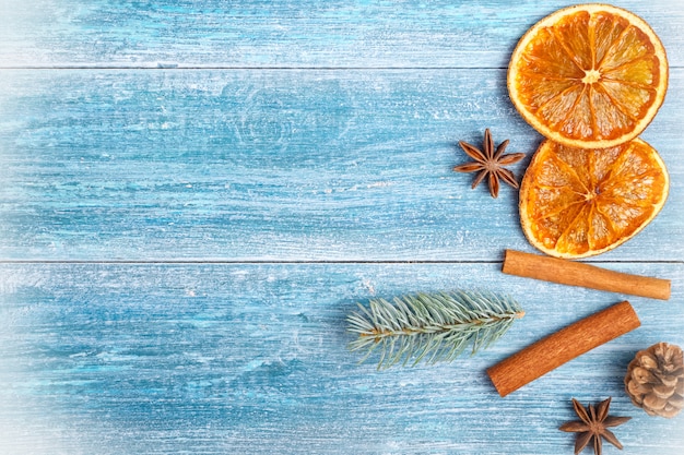 Christmas background: dried oranges, anise stars, cinnamon sticks, sprig of spruce, on a blue wooden background