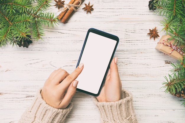 Рождественские фон: женские руки обмена сообщениями смартфон на деревенский деревянный стол