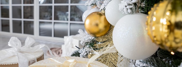 Christmas background fir tree branch with cones and ornament Christmas baubles in golden and white colours Winter holidays concept glitter Christmas baubles hanging from the branch