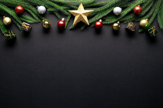 Christmas background. fir tree branches, red decorations on black background