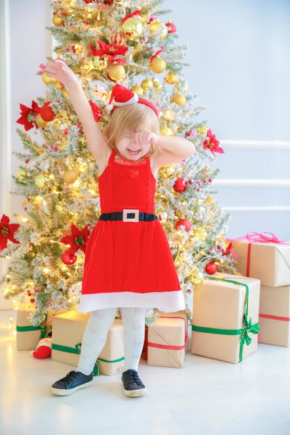 Christmas background a girl with a hat of Santa Claus stands in Christmass decorations