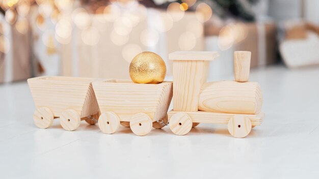 Foto sfondo natalizio trenino in legno fatto a mano sul pavimento vicino all'albero di natale festivo