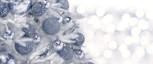Foto sfondo natalizio di palle brillanti d'argento di diverse dimensioni su un albero di natale bianco con un lato bellissimo