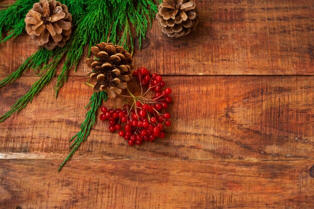 Christmas background. Spruce branches, red berries, pinecones on a wooden background. Copy space. Top view. Christmas or New Year's card. Place for text, flat lay, frame