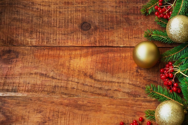 Foto sfondo di natale. rami di abete rosso, bacche rosse di potassio e palline luminose di capodanno su uno sfondo di legno. vista dall'alto. biglietto di natale o capodanno. posto per testo, copia spazio, disposizione piatta