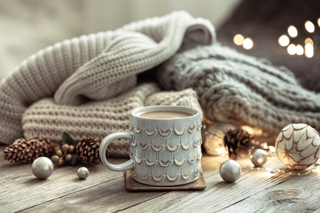 Christmas background with a beautiful cup, knitted element and decorative details on a blurred background with bokeh.