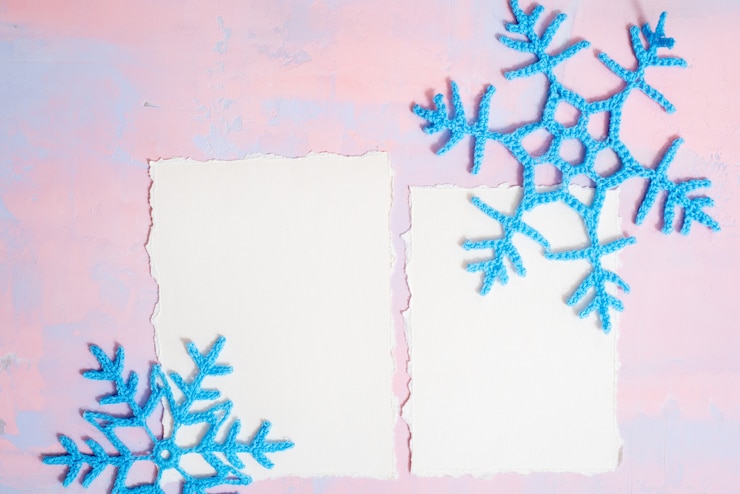 फोटो christmas background with blank notebook, blue crocheted snowflake, handmade on a purple-pink background.  torn paper trend. flat lay, top view. copyspace.