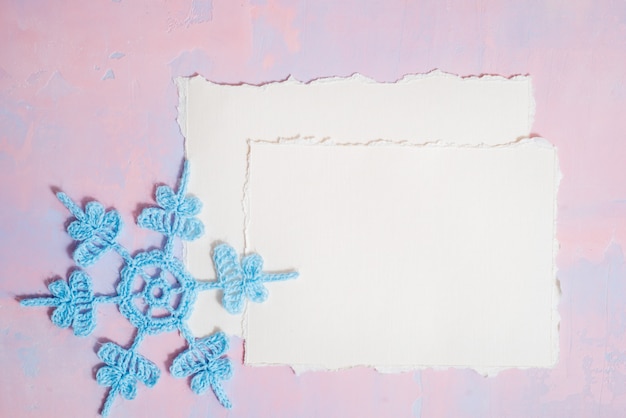 Christmas background with blank notebook, Blue crocheted snowflake, handmade on a purple-pink background.  torn paper trend. Flat lay, top view. copyspace.