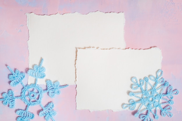 Christmas background with blank notebook, Blue crocheted snowflake, handmade on a purple-pink background.  torn paper trend. Flat lay, top view. copyspace.
