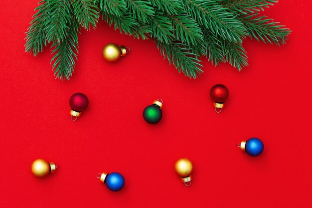 Christmas background with branches of christmas tree and many small glass balls on red paper background