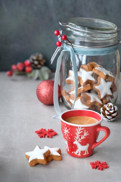 Christmas background with coffee and tasty star ginger cookies in a glass jar