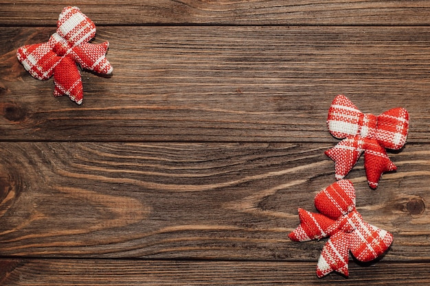 Christmas background with decorative red bows on wooden boards.