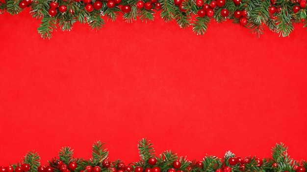 Photo christmas background with fir branches and red berries on red background top view with copy space