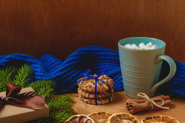 Christmas background with fir, scarf, dry orange, biscuits, cinnamon