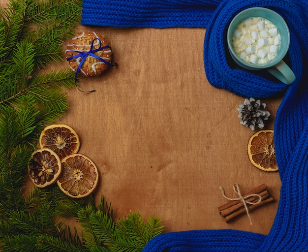 Christmas background with fir, scarf, dry orange, cone, biscuits, cinnamon