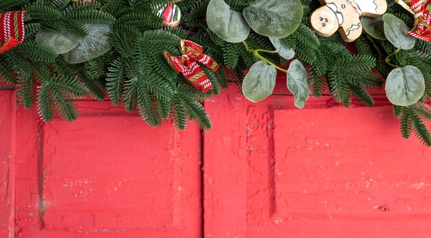 Рождественский фон с еловым деревом и новогодним украшением на красной деревянной доске