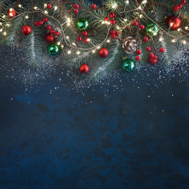 Photo christmas background with fir twigs, red berries, cones and xmas lights on dark, copy-space