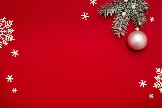 Christmas background with fir, white ball and snowflakes on red.