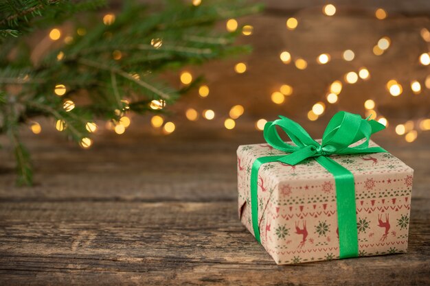 Christmas background with gift box christmas tree branch and defocused lights