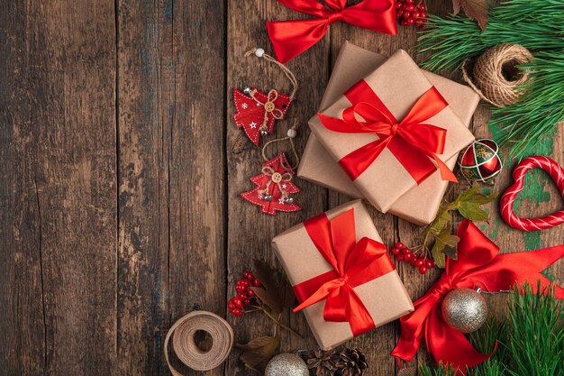 나무 배경에 빨간 리본, 크리스마스 장식, 소나무 가지가 있는 선물 상자가 있는 크리스마스 배경. 상위 뷰, 복사 공간입니다.