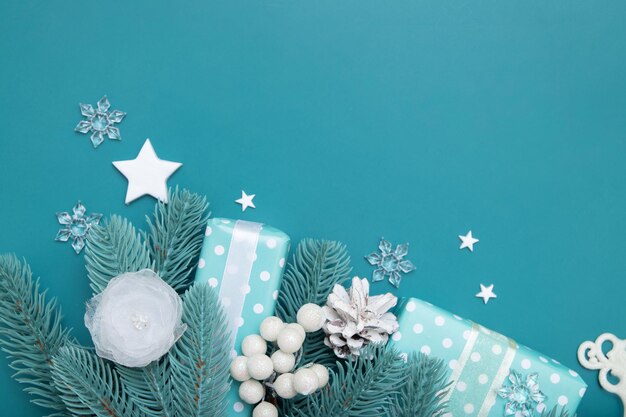 Photo christmas background with gifts, stars, berries and pine  flat lay on turquoise backdrop with copy space