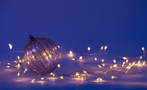 Christmas background with glass Christmas balls and a garland in blue lighting copy space