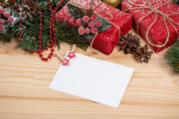 Sfondo di natale con decorazioni natalizie e carta, bacche rosse, ramo di abete e regali vista dall'alto