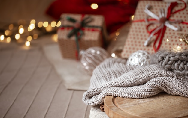 Christmas background with knitted sweater in focus on blurred background of christmas decorations and wrapped gifts copy space.