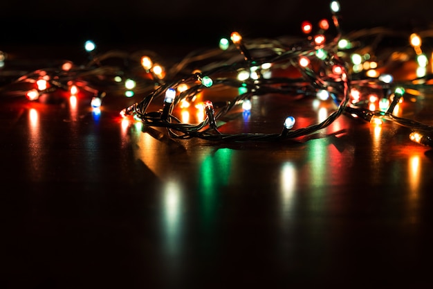 ライトとクリスマスの背景。黒の背景に輝くカラフルなクリスマスライト。