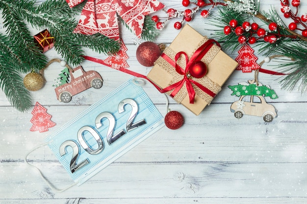 christmas background with new year decorations medical mask with numbers 2022 on wooden background