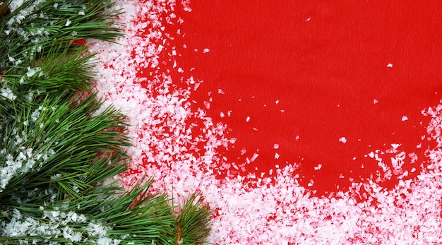 Christmas background with pine branches on a red background Festive background with artificial snow coniferous twigs and empty space