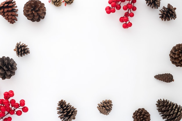 Christmas background with pine cones and holly berry on white background. Creative flat lay, top view design 