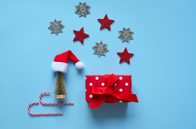 Christmas background with Santa hat, gift box, dry spices, orange rings, cinnamon, candies, sleigh